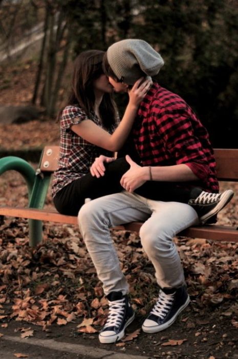 pareja de novios besandose sobre una banca en el parque
