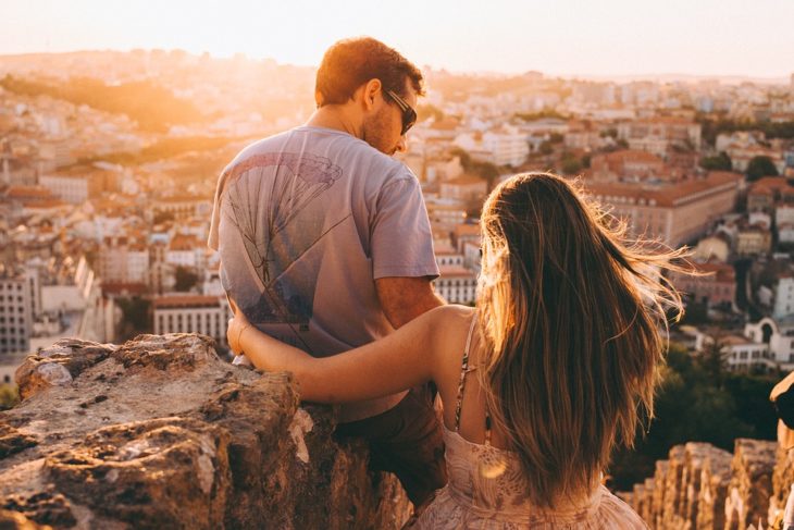 pareja observando el atardecer desde unas escaleras 