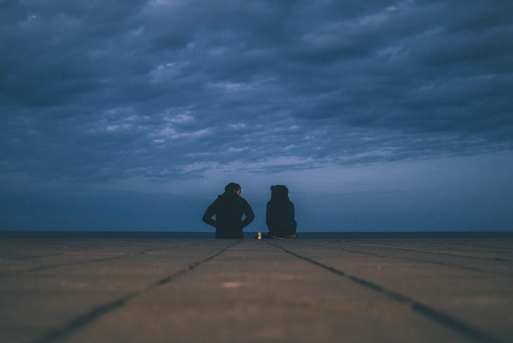pareja sentados bajo un cielo a punto de oscurecer 