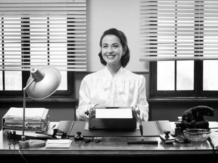 secretaria en su escritorio mostrando una sonrisa