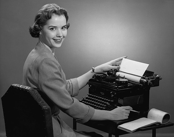 secretaria frente a su maquina de escribir sonriendo