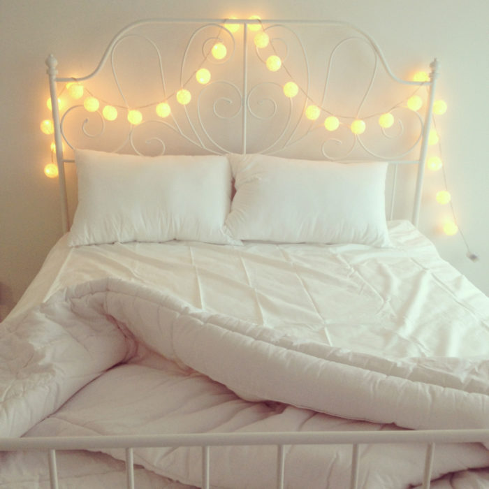 cama con sabanas blancas y luces 