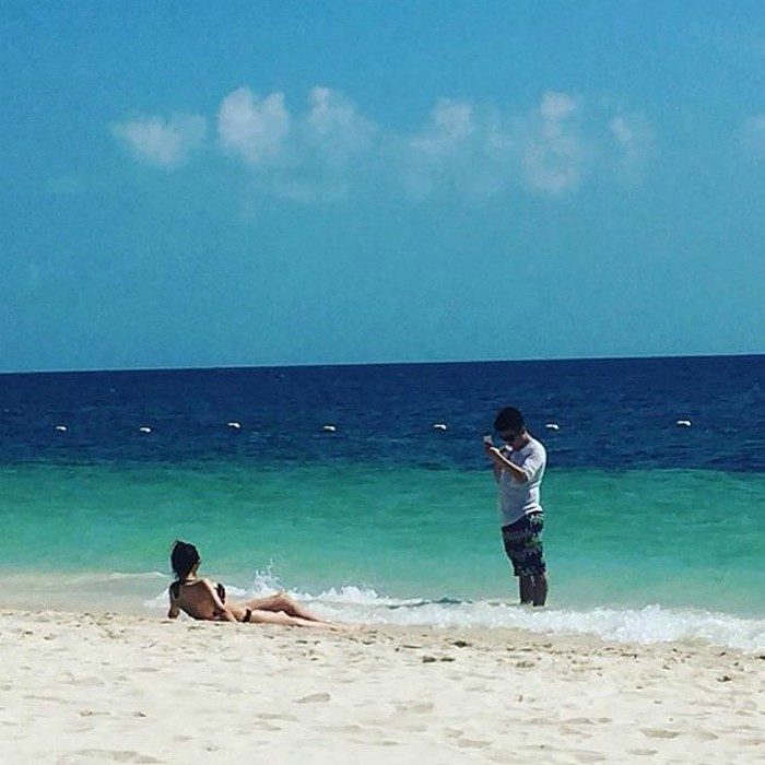 mujer acostada en la playa y hombre tomando foto 