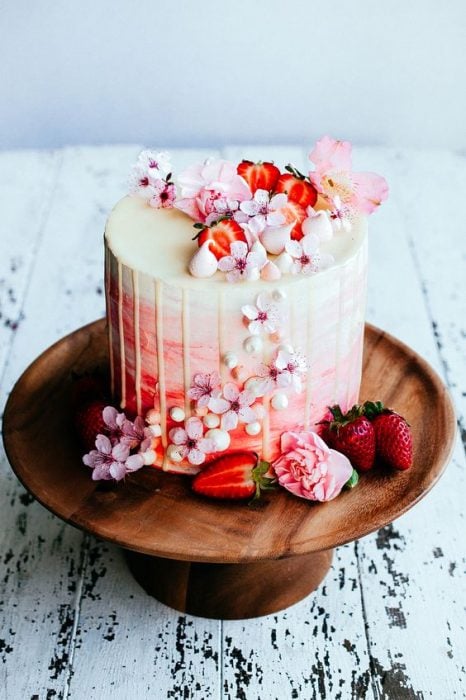 Pastel de vainilla decorado con flores naturales y fresas silvestres