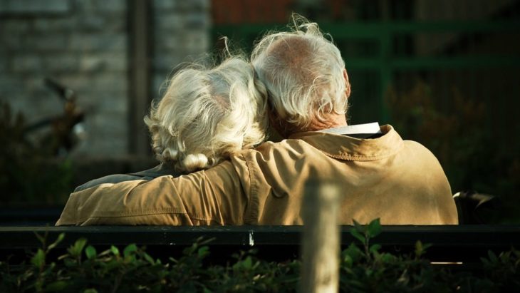 Pareja de abuelitos abrazados sentados de espaldas