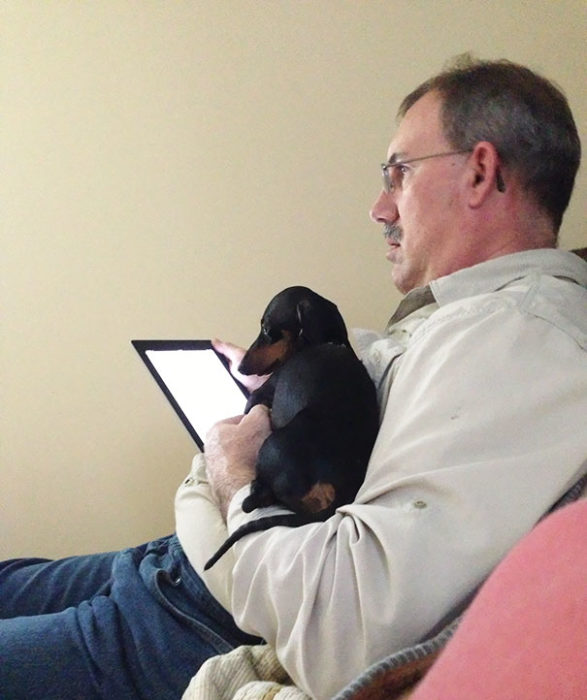 Hombre viendo su tablet junto a su perro 