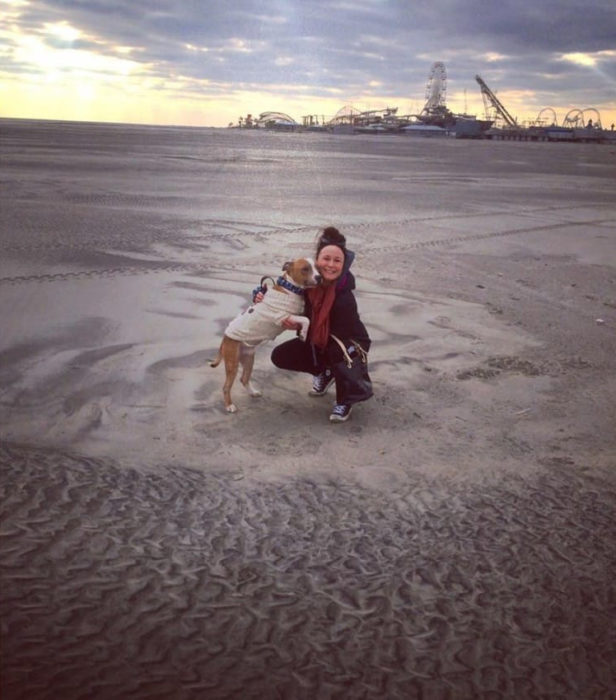 Perro y su dueña en una playa 