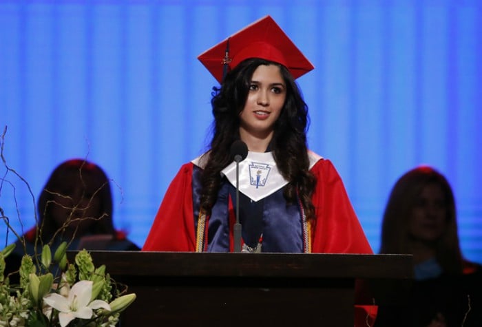 mujer con toga y birrete dando discurso de graduación