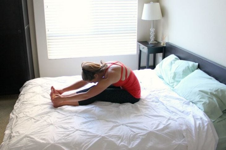 Chica practicando yoga en la cama