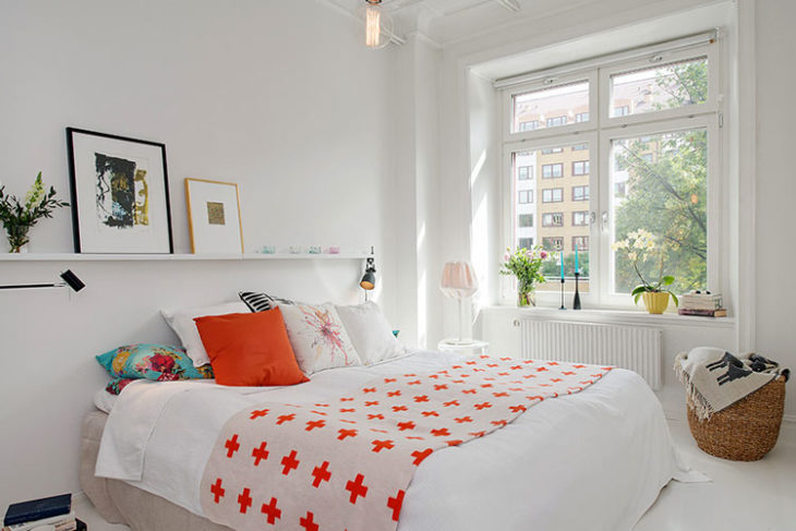 cama tendida habitación blanca con naranja