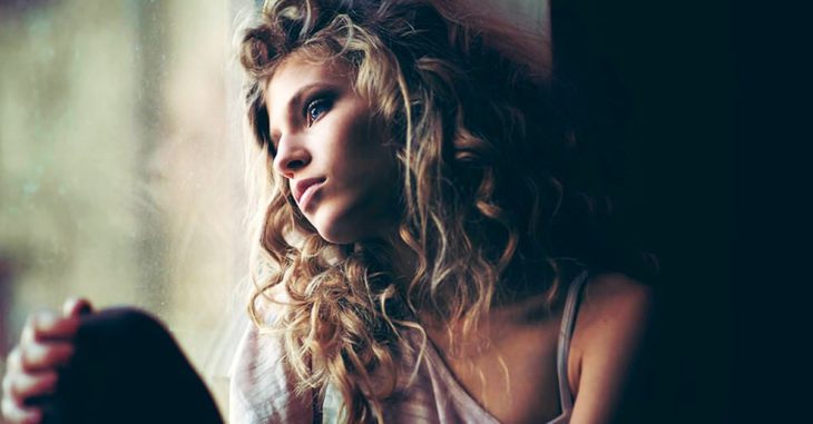chica triste viendo por la ventana