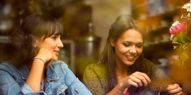 dos chicas platicando a través de un cristal