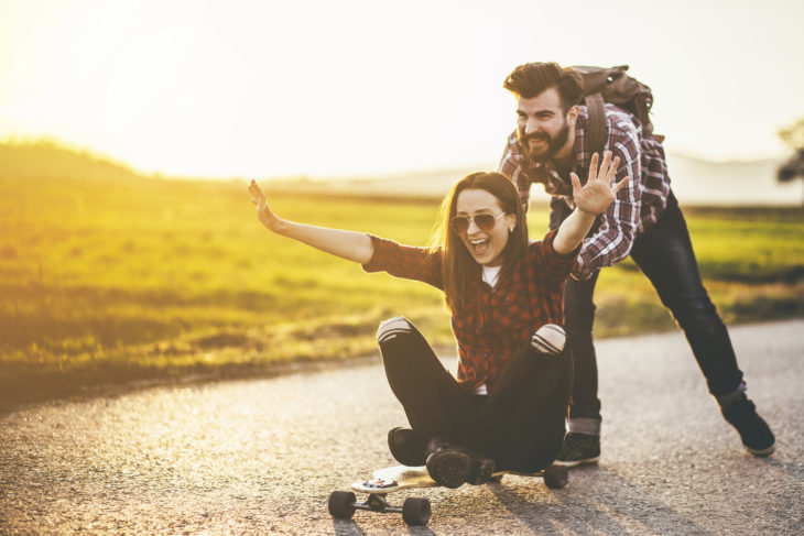 un novio empujando a su novia que esta sentada en una patineta