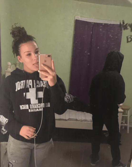 mujer tomandose selfie y hombre atrás