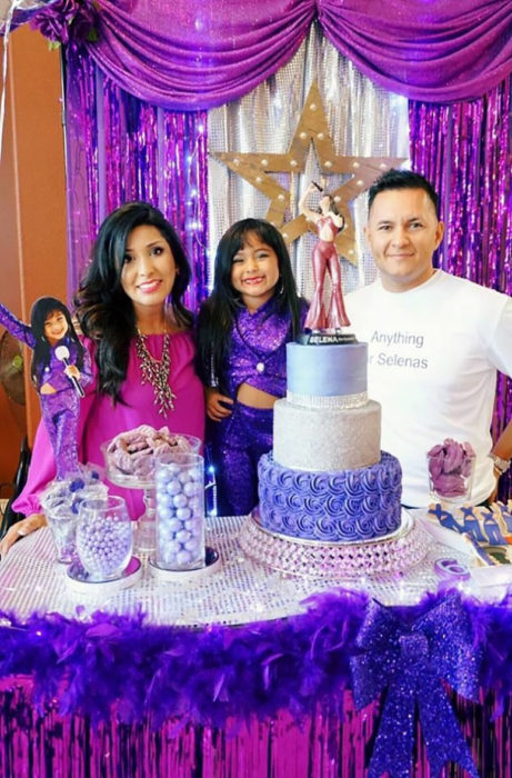 niña al lado de madre y padre con pastel 