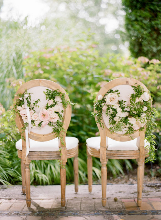 Sillas de una boda decoradas con hiedra en verde y rosas