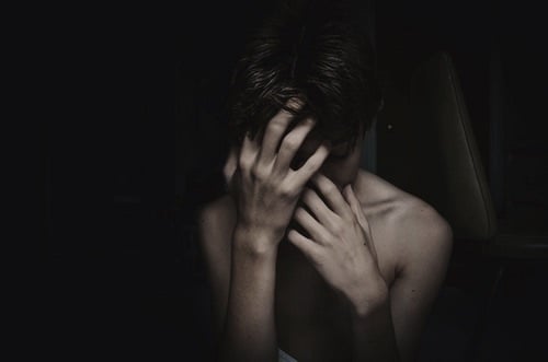 chico con ansiedad y depresión cubriéndose el rostro