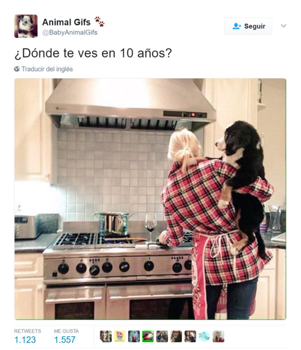 Chica cargando a un perro mientras cocina 