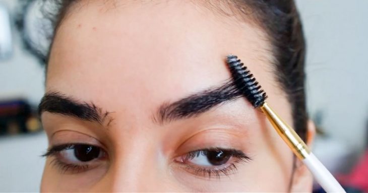 mujer cepillando sus cejas 