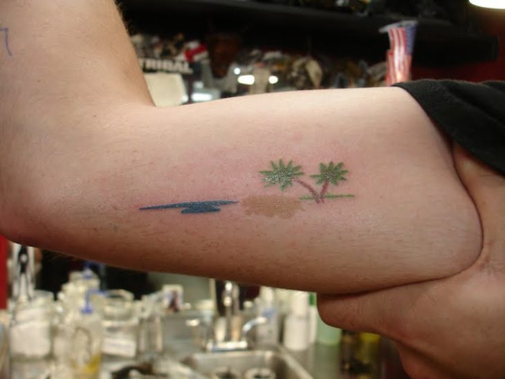 Chica con una isla tatuada en el brazo 