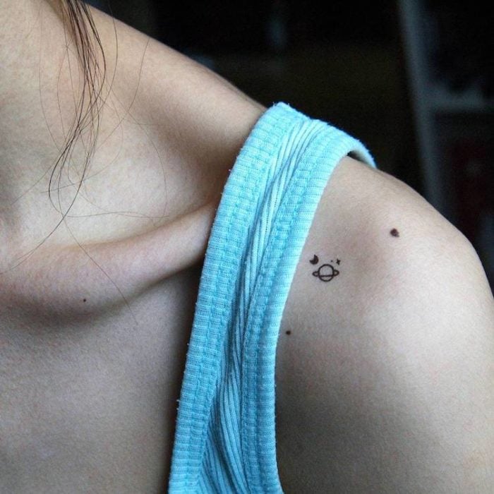 Chica con un planeta tatuado en su brazo 