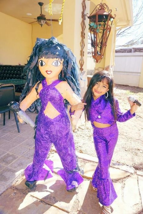 niña con ropa morada al lado de piñata 