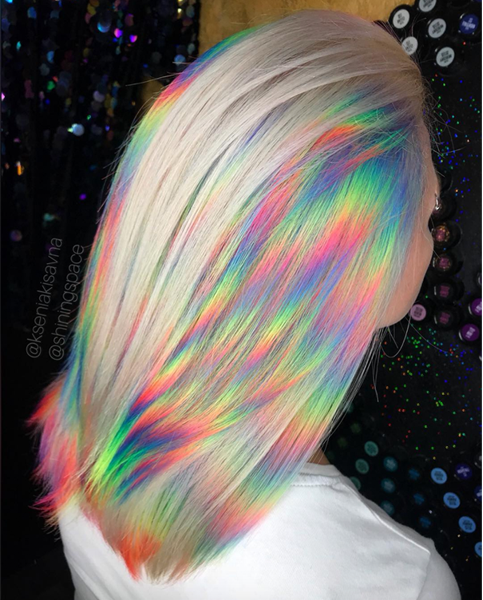 Chica de espaldas mostrando su cabello rubio con mechas holografícas de colores 