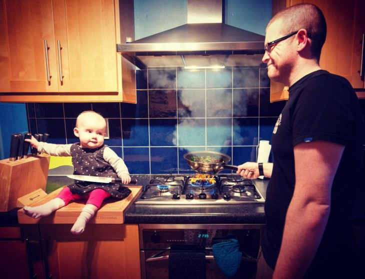 Niña en la cocina cocinando junto a su padre