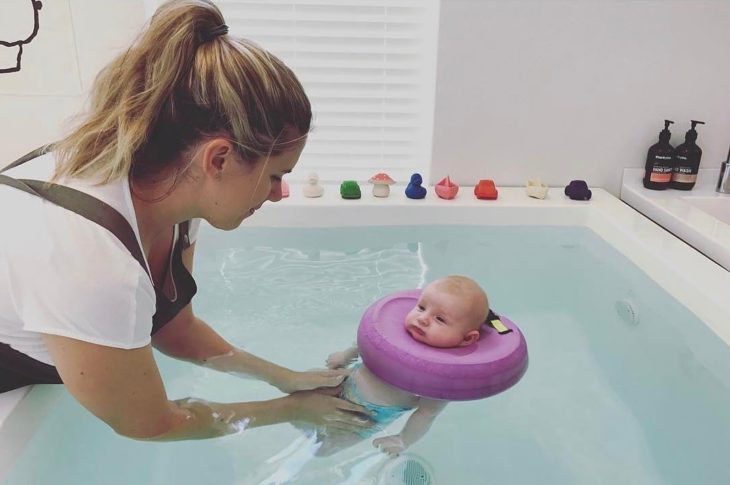 mamá sosteniendo a su bebé mientras está en la alberca 