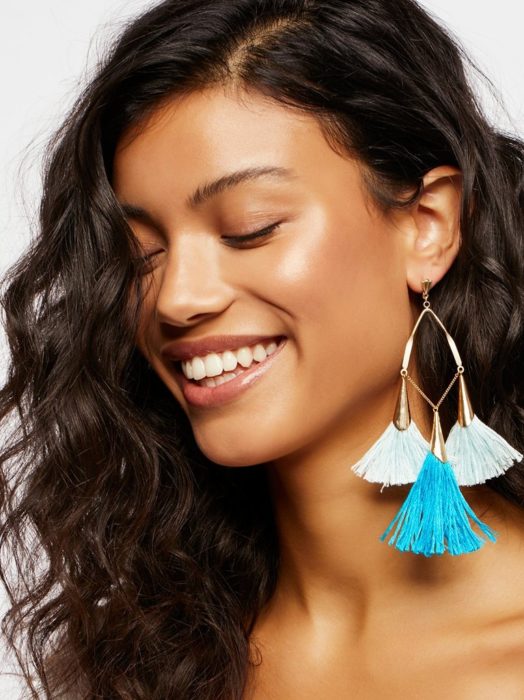 Chica usando unos aretes azules con blanco 