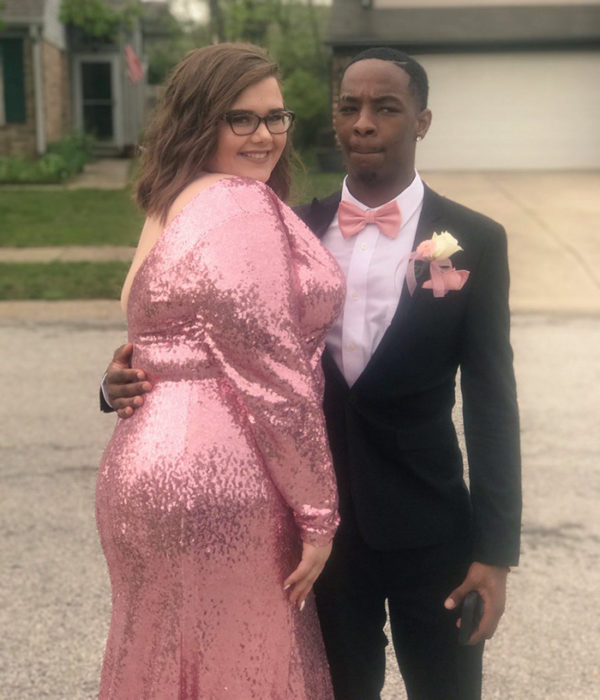 Chica posando junto a su novio en el baile de graduación 