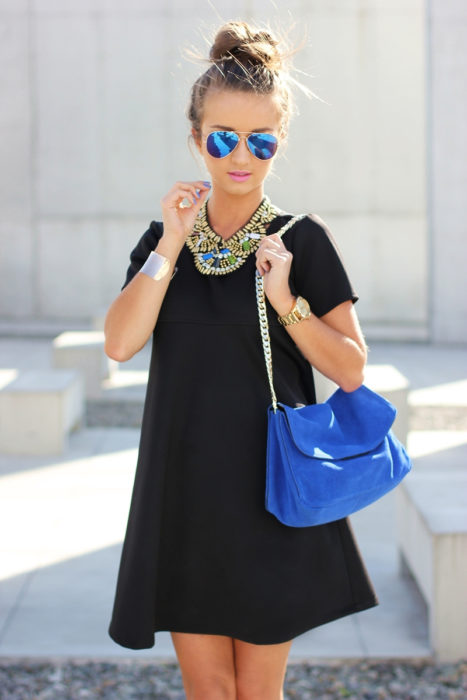 Chica usando un vestido negro y accesorios dorados