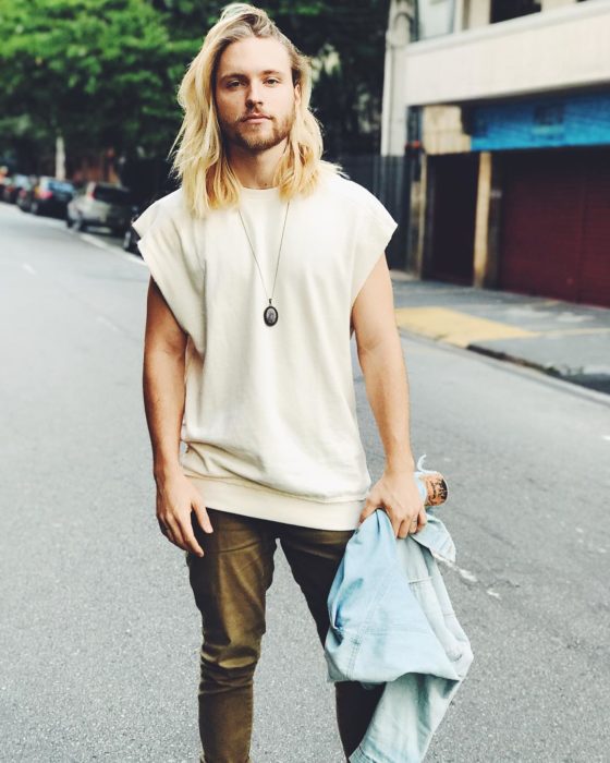 hombre rubio de cabello largo con playera blanca 