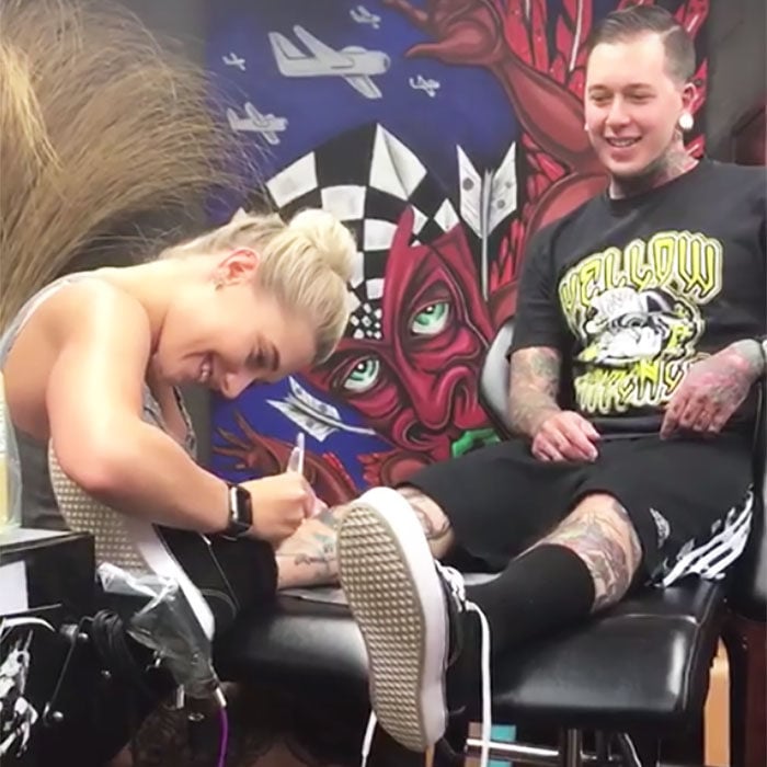 Chica tatuando la pierna de su novio 