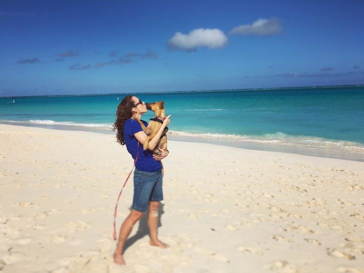 Mujer besando a un perro en la playa