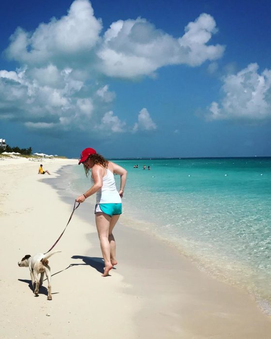 Mujer paseando a un pero en la playa