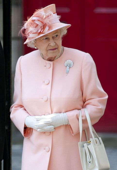 Mujer anciana reina con sombrero rosa y plumas