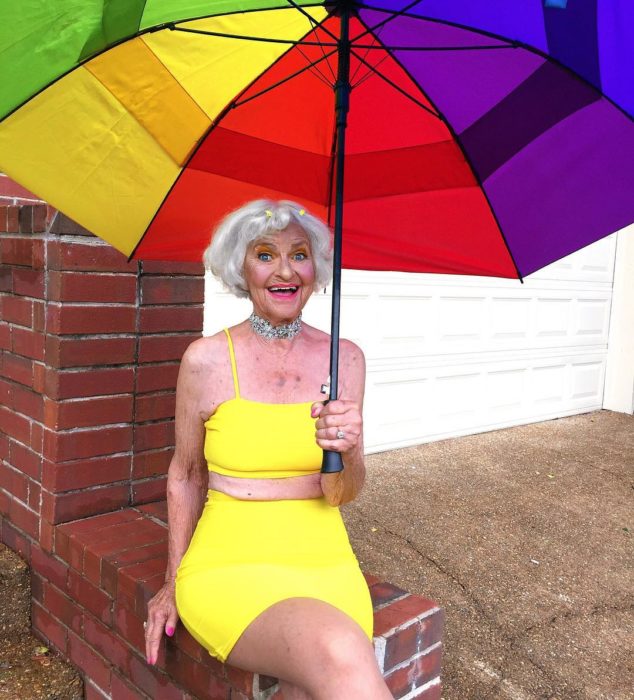 Baddie winkle posando en crop top y falda de lapiz color amarilla mientra sostiene una sombrilla 