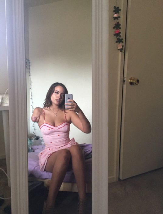 Chica sin un brazo sentada tomándose una selfie