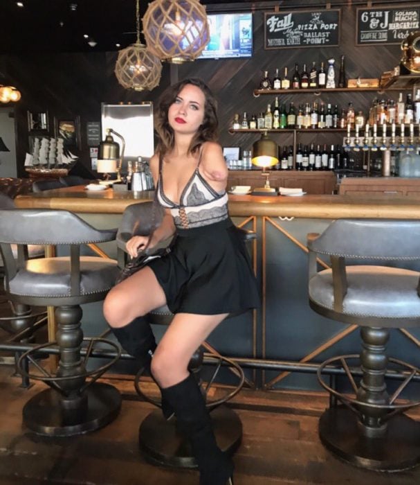 Mujer sin un brazo posando para una sesión de fotos en un bar 