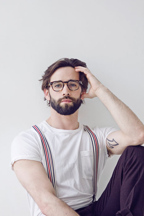 chico con barba y cabello largo usando tirantes 