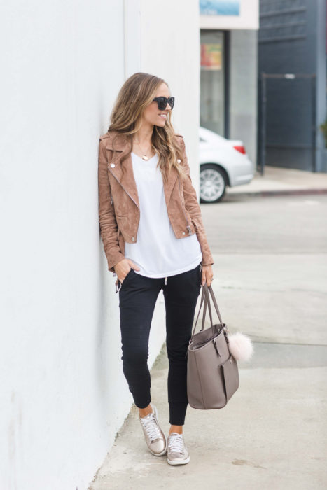 Chica usando unos jogger pants chamarra de cuero y blusa blanca 