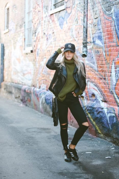 Look con gorras chica usando gorra negra con jeans negros y chamarra de piel 