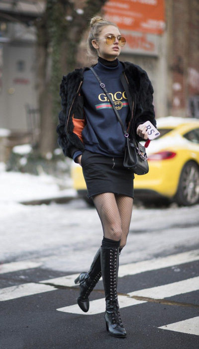 Chica usando un look con sudadera, falda y botas