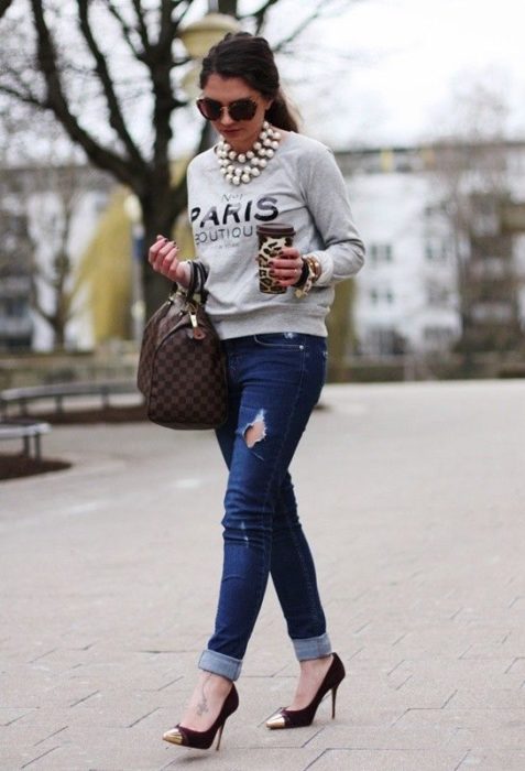 Chica usando un look con sudadera jeans y stilletos