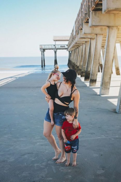 Mujer paseando junto a sus dos hijos en la palaya