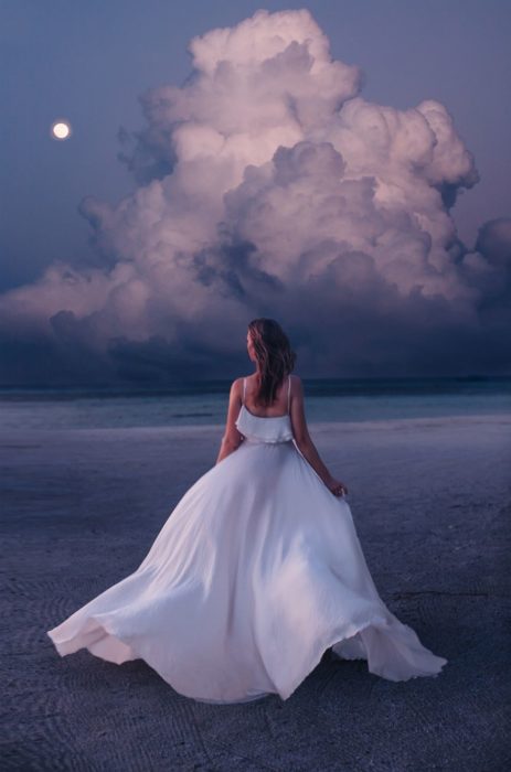 Mujer usando un vestido y posando junto a las nubes 