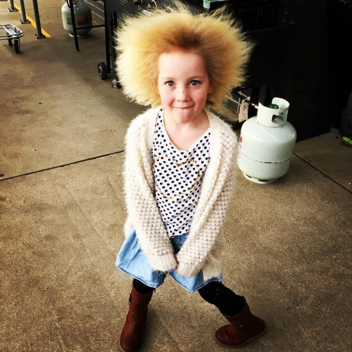 Niña con cabello rubio suéter blanco y falda