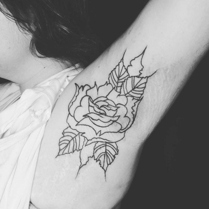 Chica con un tatuaje en la axila de una flor 
