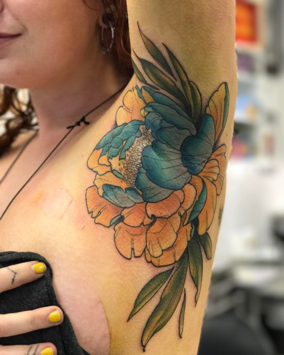 Chica con un tatuaje en la axila de una flor 